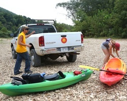 Two people unloading kayaks to float the river