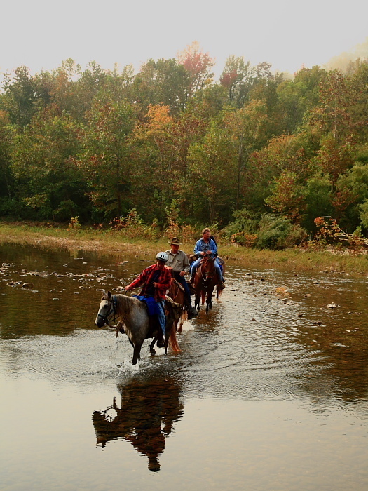 3 people riding horses in the river